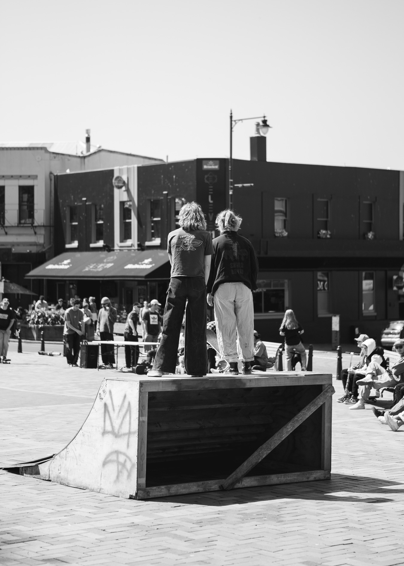 Two people standing on the platform of a skateboard quarter pipe.