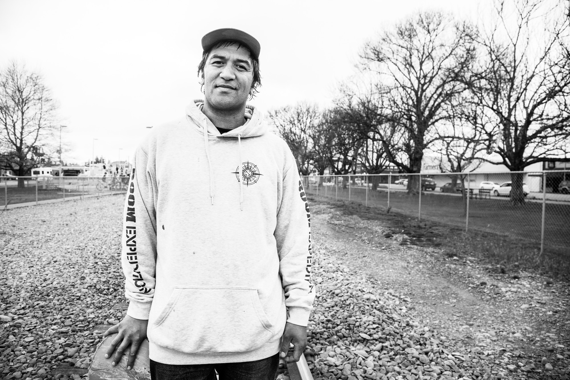 Black and white portrait of skateboarder Pauly Kauri standing on the train tracks in Ashburton.