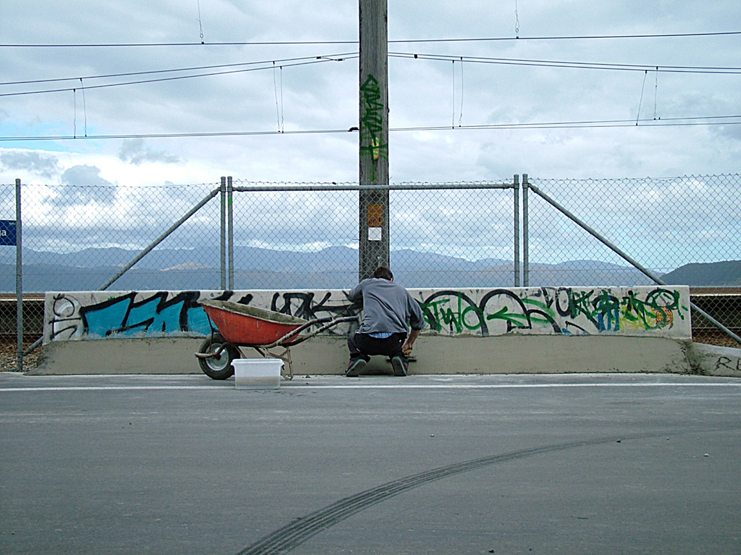 A worker enhancing a road barrier for the purpose of skateboarding.