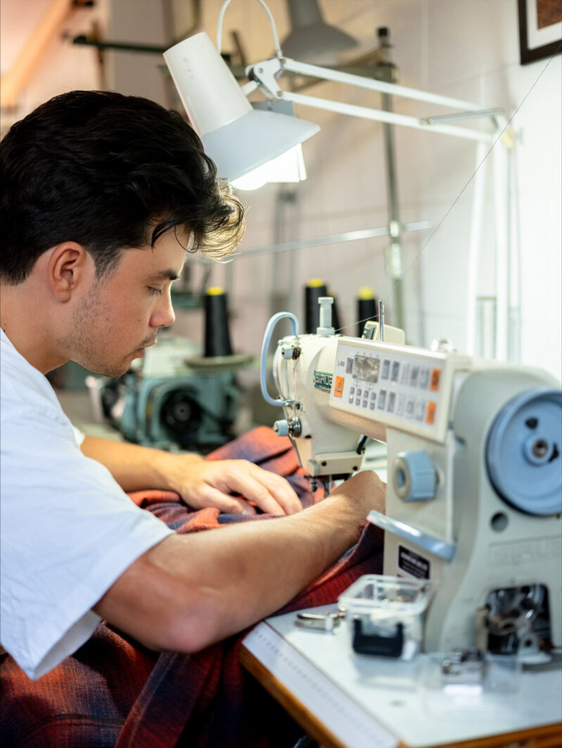 Dereck De Souza sewing on his machine at his Birkenhead studio. Photo by Jerome Warburton.